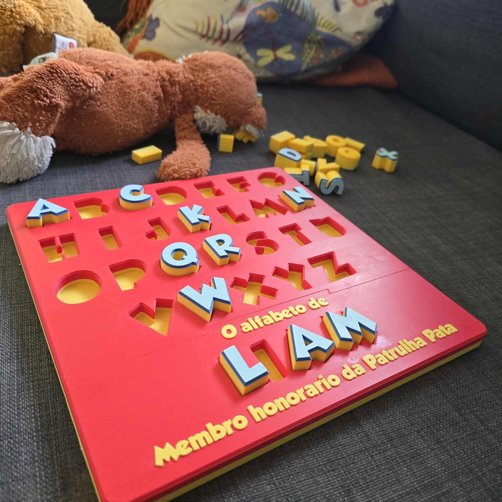 An alphabet board resting on a couch, every letter in its pocket